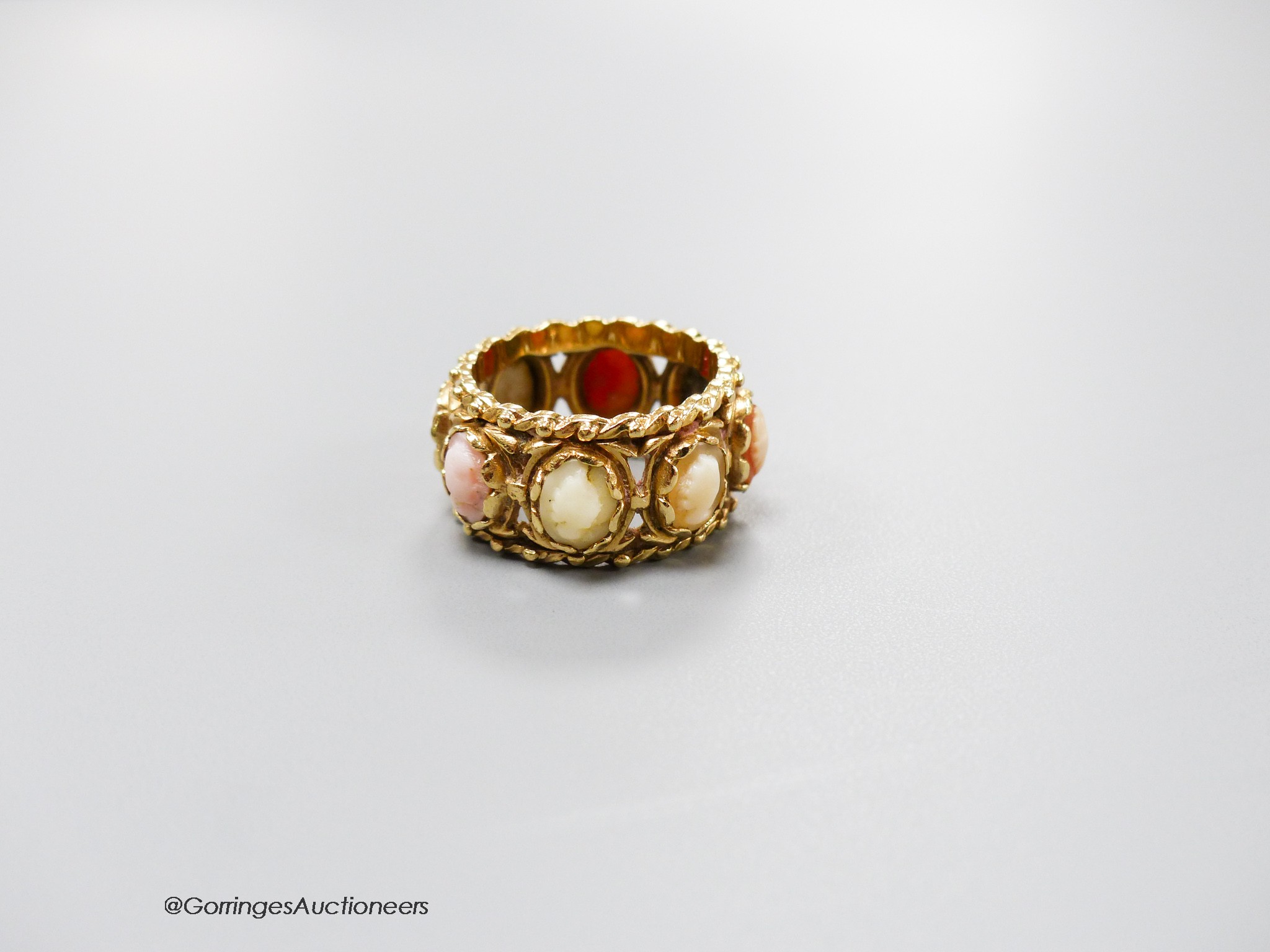 A 14kt yellow metal and multi cameo stone set eternity ring, including shell and coral, size P, gross weight 9.2 grams.